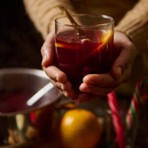 Close-up of hands holding a festive drink, evoking warmth and holiday celebration joy.